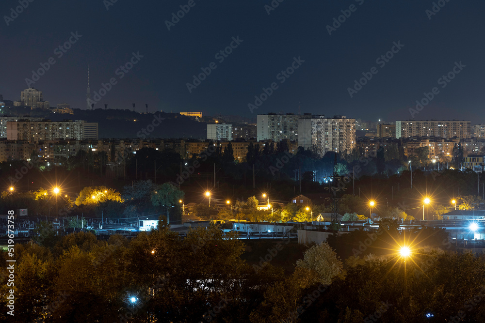 Night cityscape of the big city. Awesome bright, multi colored light at curfew on empty streets. Apartment buildings in bedroom community, commuter town area. Kyiv in last days in july 2022. Ukraine.