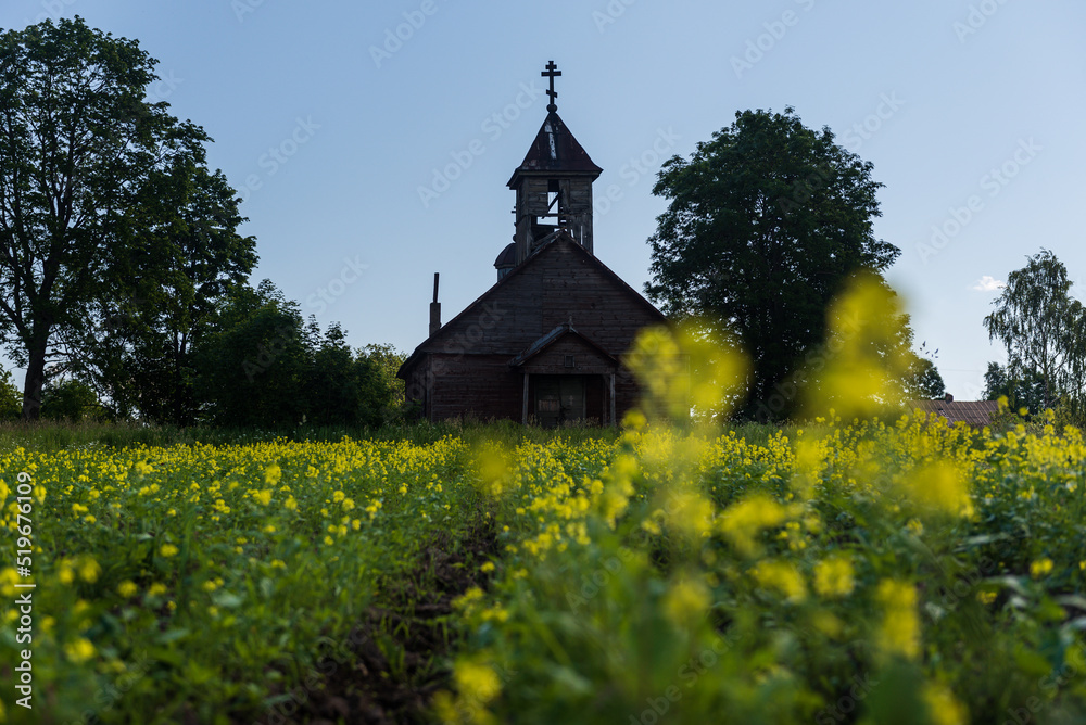 Silhouette of abandoned Bondariski Old Believers Church and rapeseed field in summer day, Latvia.