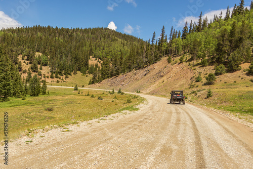 Fotografie Road in the mountains with people riding in a side by side UTV