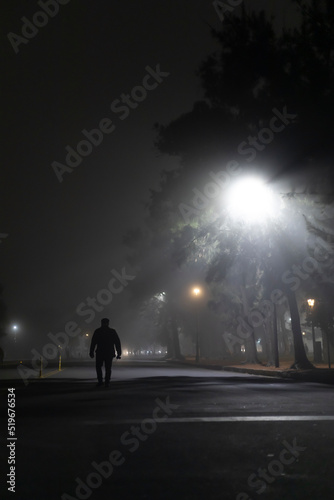 Hombre solitario caminando de noche en la niebla