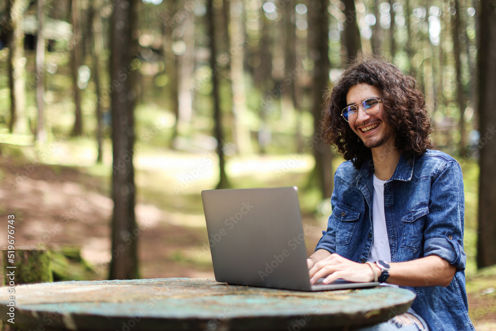 Young latin man sitting in the forest working with laptop freelancing looking camera smiling at Costa Rica Young latin man sitting in the forest working with laptop freelancing looking camera smiling at Costa Rica