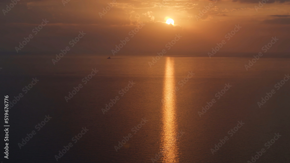 Aerial view of a golden sunset sky background with evening clouds over the sea. Shot. Stunning sky clouds in the sunset with a bright sun path on the sea surface.