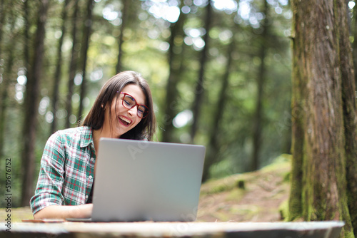 Young latin woman sitting in the forest working with laptop freelancing smiling at Costa Rica