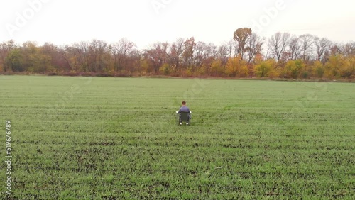 Aerial drone view of IT Programmer working on laptop outdoor on spring meadow. Male Software Engineer Developing App, Video Game. 