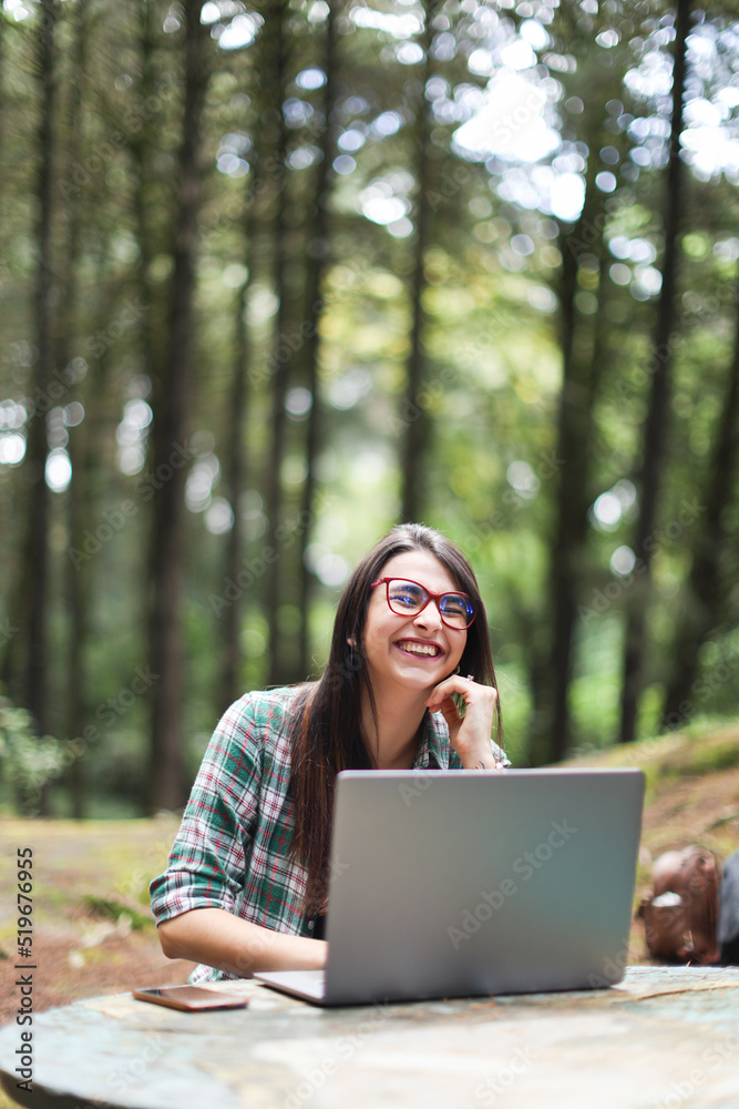 Young latin woman sitting in the forest working with laptop freelancing smiling at Costa Rica Young latin woman sitting in the forest working with laptop freelancing smiling at Costa Rica