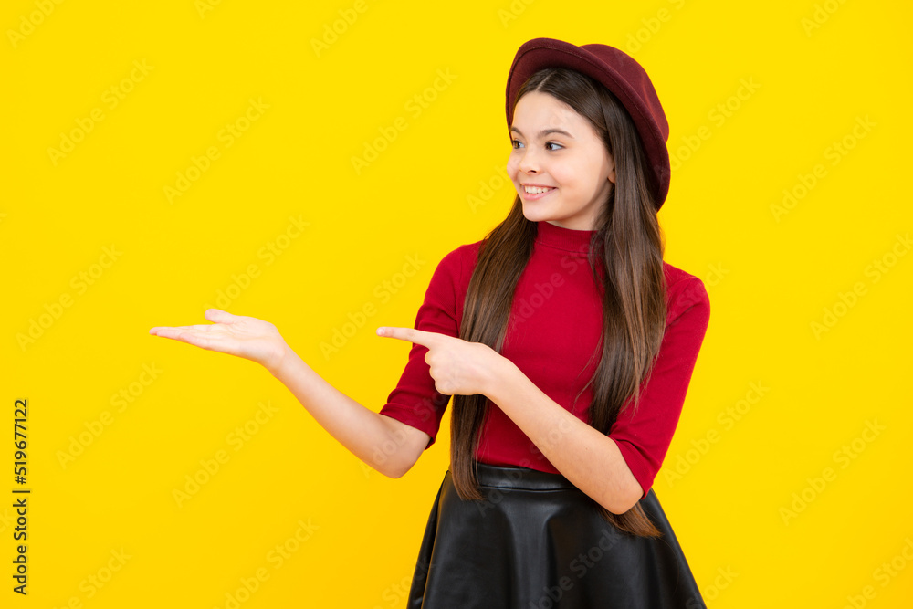 Impressed teenage girl showing recommendation copyspace. Child teenager points away, pointing aside at copy space. Happy teenager portrait. Smiling girl.