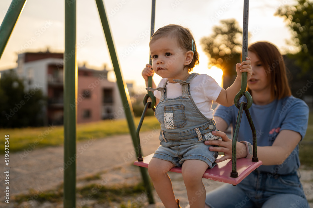 mother and daughter little toddler girl child on swing in park mother and daughter little toddler girl child on swing in park