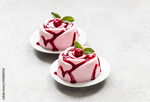 Cherry cream pudding, Panna Cotta with sauce, in the shape of a rose, on a plate. Light grey background