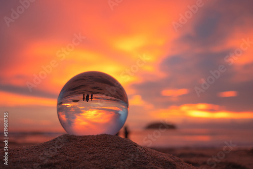 .view of beautiful nature at sunset inside crystal ball..stunning sunset over sea in a crystal ball on the beach. .A image for a unique and creative travel.