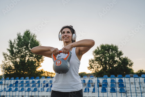 Caucasian woman with kettlebelk girya training in stadium outdoor