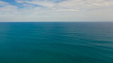 Open blue ocean with waves against the sky and clouds, top view.