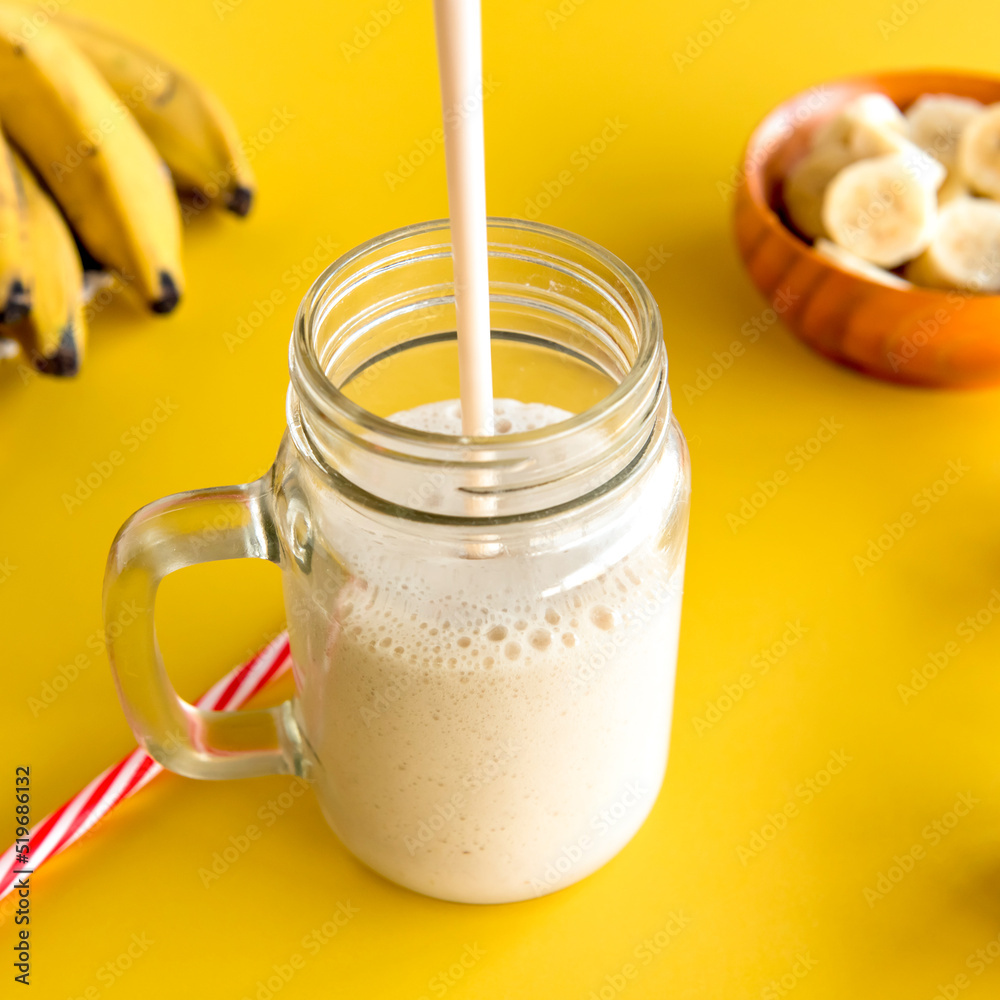 Banana smoothie, healthy shake with banana and milk on yellow background. Banana smoothie, healthy shake with banana and milk on yellow background.
