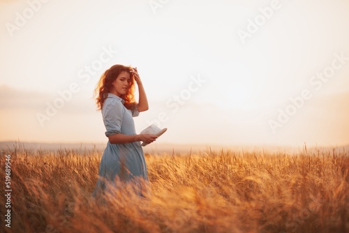 Woman in the field with flowers on sunset background