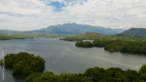 Aerial view of lake with islands surrounded by mountains with a tropical forest. Loggal Oya Reservoir. Sri Lanka.
