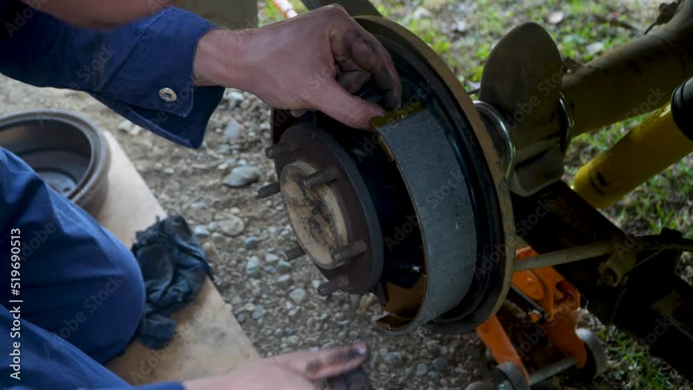 Automotive repair technician installs new brake pads on car or truck, outdoors close up Automotive repair technician installs new brake pads on car or truck, outdoors close up