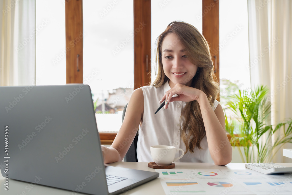 Attractive smiling young asian woman on a video call by laptop computer Attractive smiling young asian woman on a video call by laptop computer