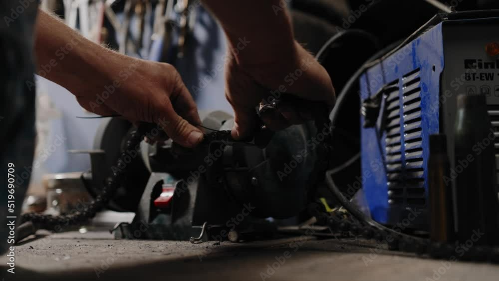 Close up shot of mechanic breaking a chain open with a whetstone Close up shot of mechanic breaking a chain open with a whetstone