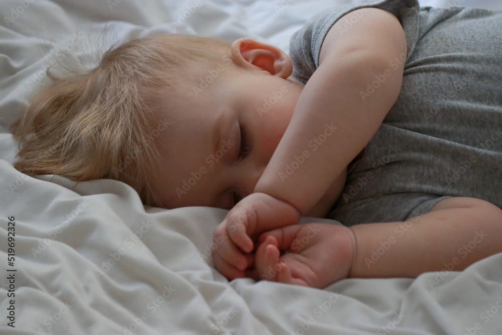 close up of sleeping baby boy 9 months old, bed with white sheets close up of sleeping baby boy 9 months old, bed with white sheets