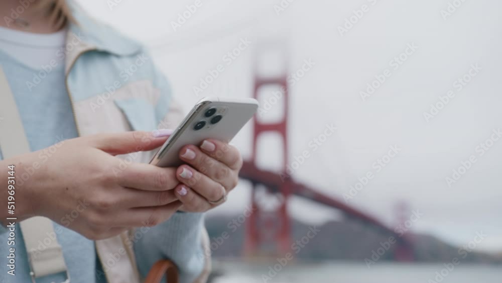 Close up young woman tourist hands browsing online on smartphone in San Francisco with Golden Gate bridge on motion background. Cinematic travel booking, purchase airplane tickets concept RED video Close up young woman tourist hands browsing online on smartphone in San Francisco with Golden Gate bridge on motion background. Cinematic travel booking, purchase airplane tickets concept RED video