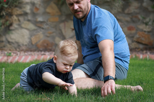 father and baby son playing together outside on green grass