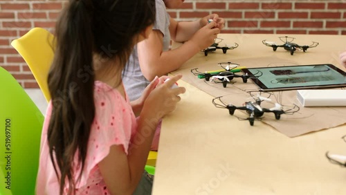 Students building, testing and designing scientific drones, batteries and electrical equipment from tablet. Group of diverse children following engineering tutorial for middle school science project photo