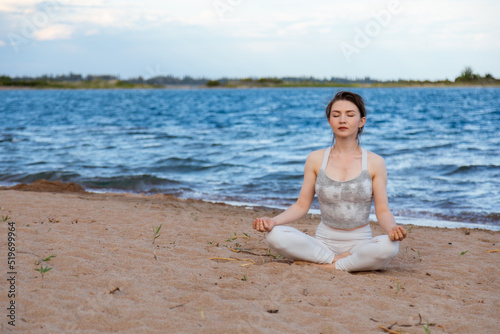 Woman practicing yoga outside in lotus pose on beach © Collab Media