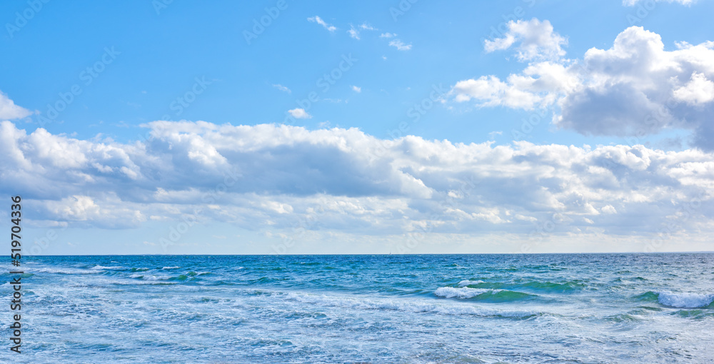 Beautiful, blue ocean view of the sea with white clouds on a beach day in summer. Outdoors tidal landscape of calm water, sky and waves in nature. Peaceful outdoor coastal setting outside.