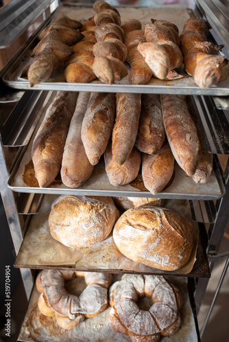 Finished French bread in the bakery on the racks. Baguettes, rustic bread, crown of kings Bordeaux. Vertical photo.