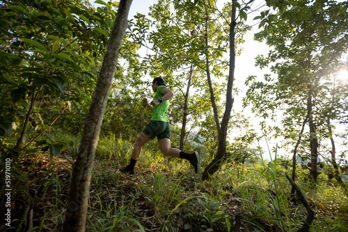 Woman trail runner running at sunrise tropical forest mountain peak