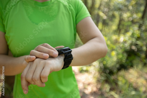 Woman trail runner set the sports watch in forest