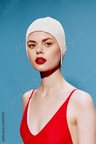 A swimmer in a red swimsuit and a swimming cap looks at the camera. Art fashion concept for banner design