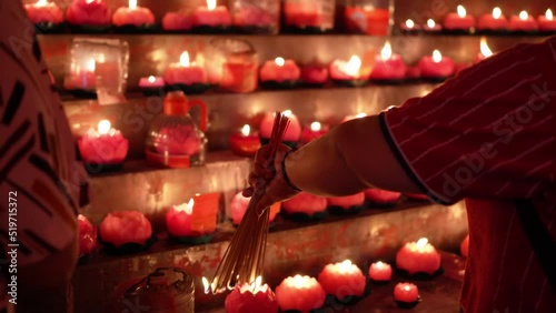 Close up the hand of chinese devotees burn the incense joss stick with lotus candle
