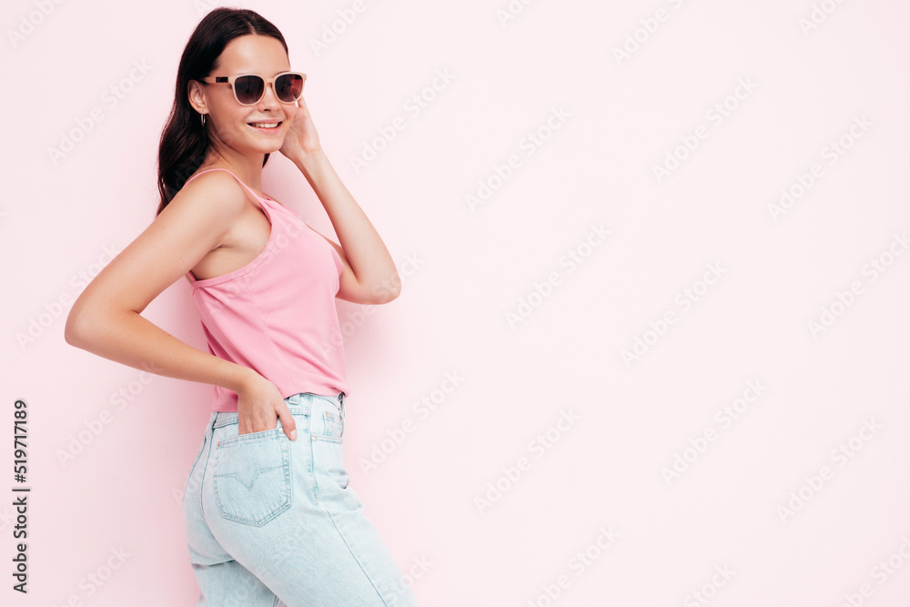 Closeup portrait of young beautiful smiling female in trendy summer clothes. Sexy carefree woman posing near pink wall in studio. Positive model having fun indoors. Taking off sunglasses Closeup portrait of young beautiful smiling female in trendy summer clothes. Sexy carefree woman posing near pink wall in studio. Positive model having fun indoors. Taking off sunglasses