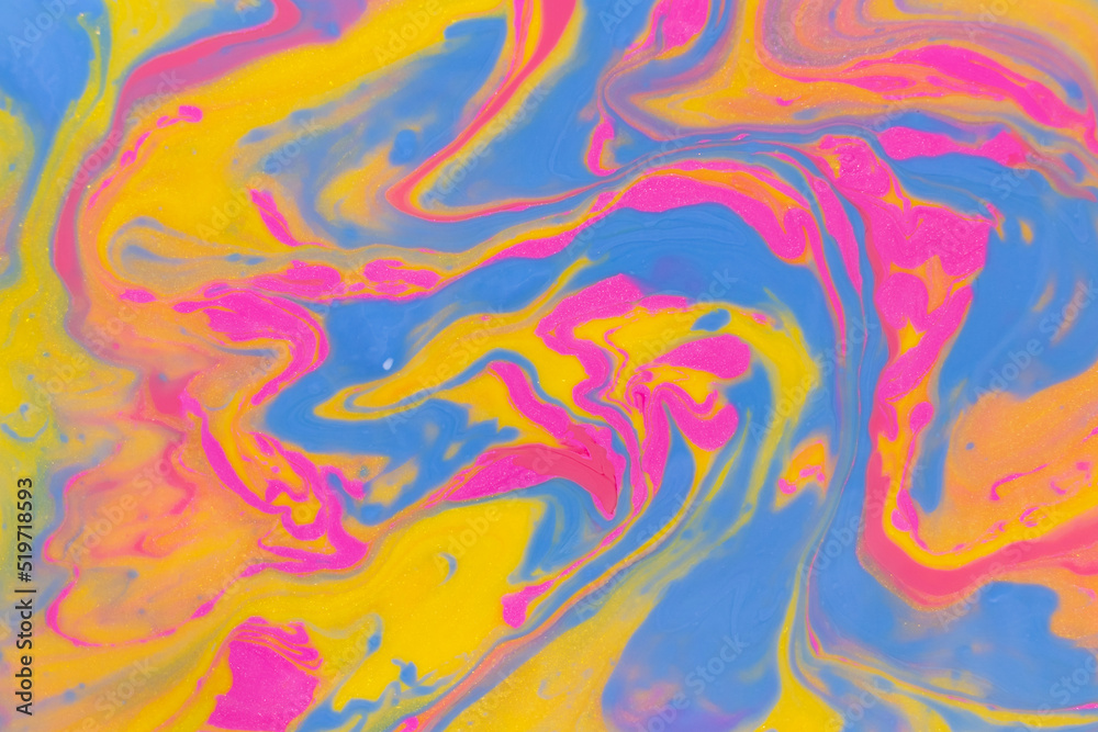 Abstract background of mixed shades of nail polish with a shiny marble pattern. Liquid colorful paint background creative yellow and pink with shimmer and blue