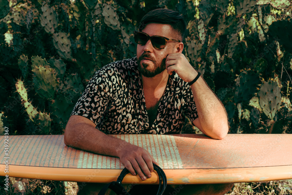 Mężczyzna surfer z deską surfingową, idący wybrzeżem na tle jungle, aktywny wypoczynek.