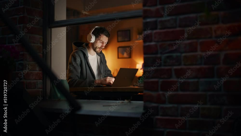 Professional Software Engineer Working From Home Office. Tired IT Specialist Feeling Sleepy and Finising Important Project. Software and Application Development. View From Outdoors into Window. Professional Software Engineer Working From Home Office. Tired IT Specialist Feeling Sleepy and Finising Important Project. Software and Application Development. View From Outdoors into Window.