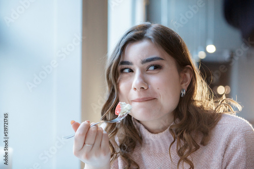 Smiling woman eating a sweet dessert in cafe.