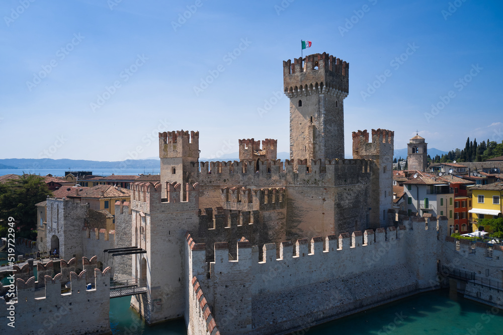 Italian flag on the main tower of Scaligero Castle Sirmione, Lake Garda. Lago di Garda, Lombardy region of Italy drone view. Aerial view of Sirmione, Lake Garda.