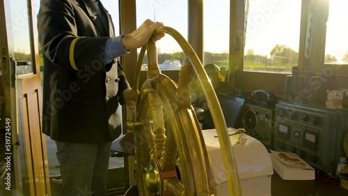 close up of a captain pulling the stearing wheel during golden hour photo