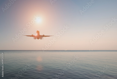 Passenger plane over the sea at sunset. Evening sea landscape. Airliner in the sky