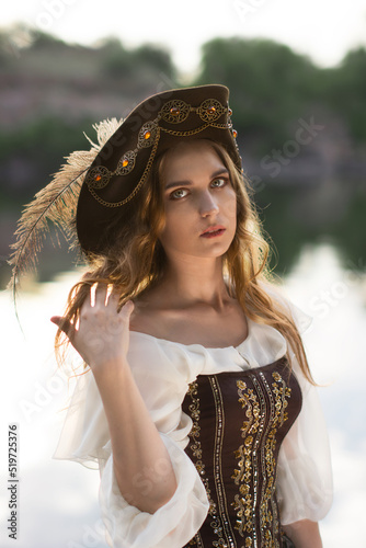 Bright color photo of a beautiful pirate girl in a hat with a feather on the shore, shot with depth of field and bokeh