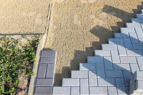 Paving the road from garden bricks by a professional paver. Laying gray concrete paving slabs on a gravel and sand base.