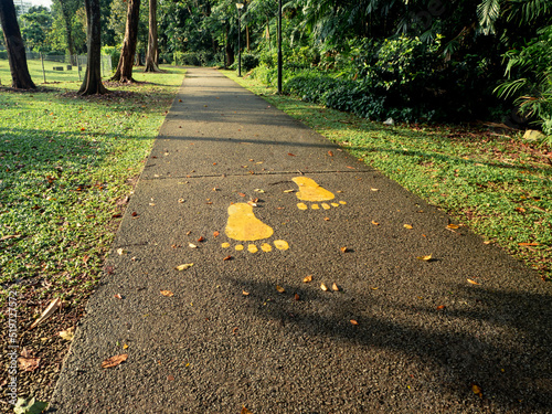 A set of yellow footprints sign on a walking path in the park