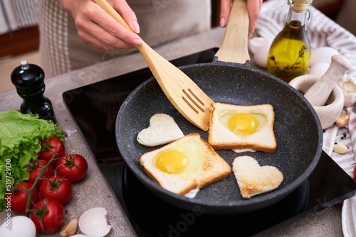 Fried egg Toasts with heart shaped holes on frying pan