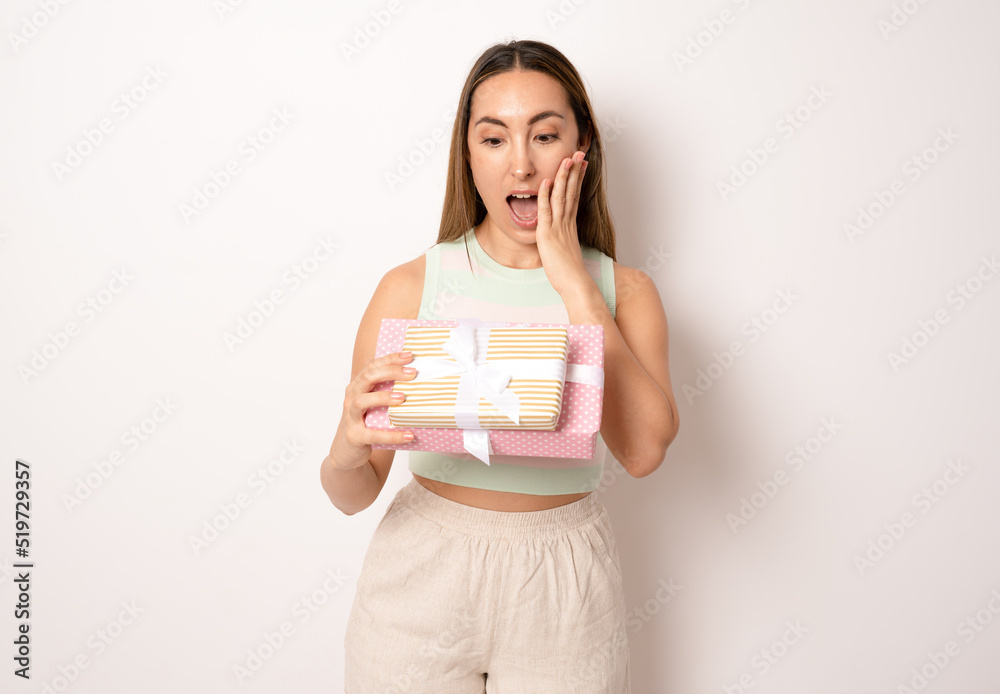 Amazed young brunette woman holding gifts standing isolated over white background. Amazed young brunette woman holding gifts standing isolated over white background.