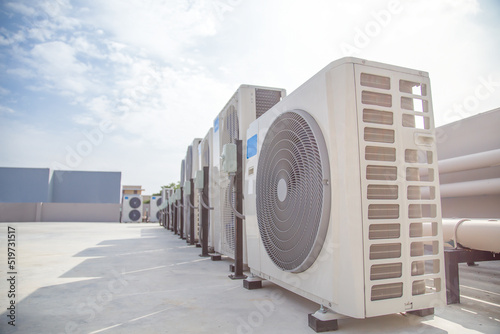 Air conditioning (HVAC) on the roof of an industrial building with blue sky and clouds. 