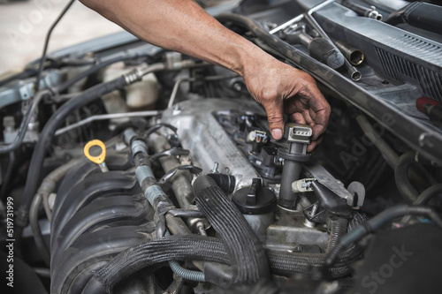 Auto mechanic testing an engine ignition coil on a Car. photo