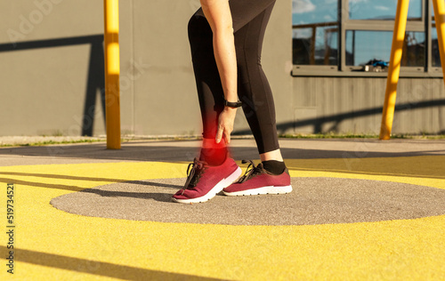 Sore ankle in sports. Woman holding painful foot with red spot. Ligaments injury. Health problems concept. High quality photo