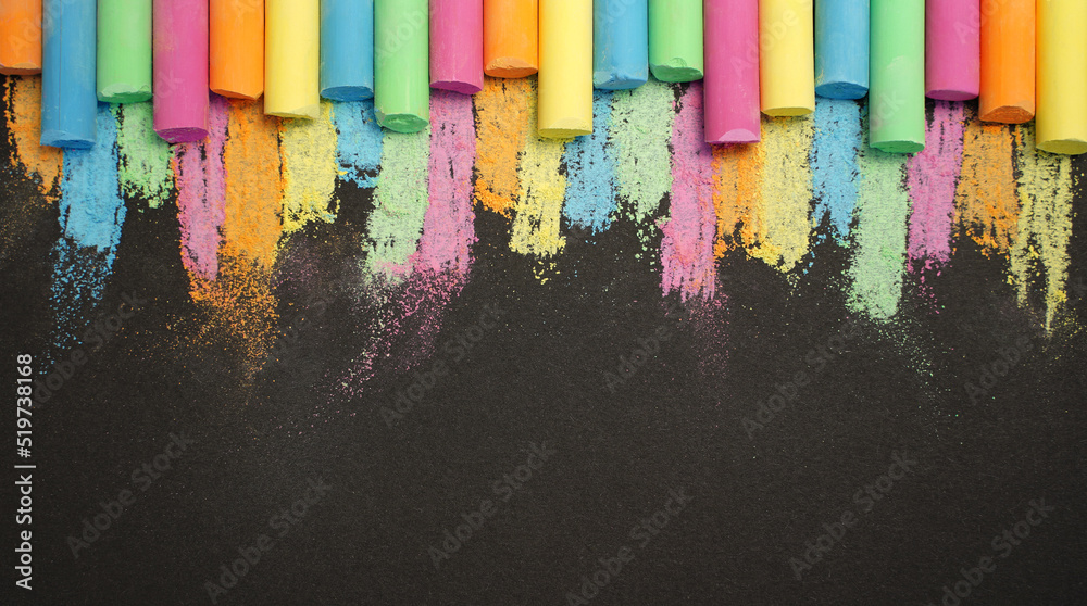 Multicolored chalk in row on black background. Education concept back to school. Copy space for your text. Banner - obrazy, fototapety, plakaty 