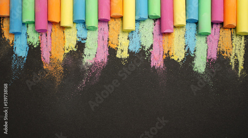 Multicolored chalk in row on black background. Education concept back to school. Copy space for your text. Banner